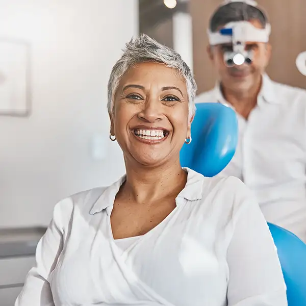 A smiling woman sitting in dental chair in front of dentist