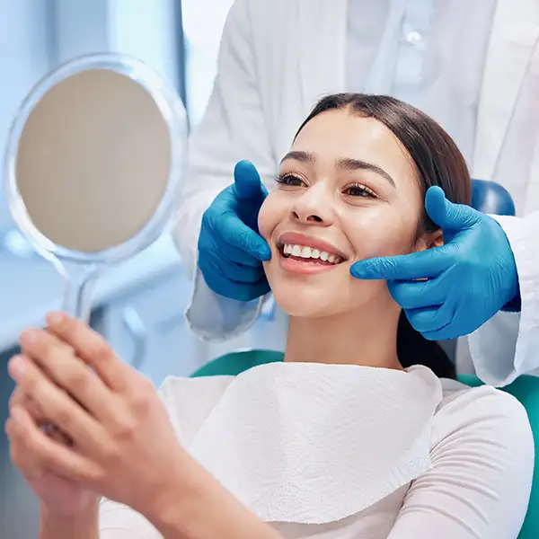 Smiling patient sitting in dental chair and looking up at mirror